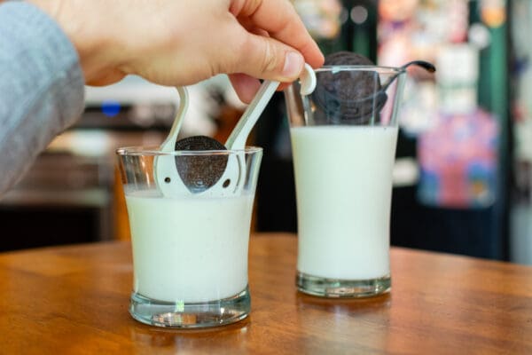 A person is stirring milk in two glasses.