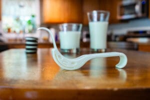 A wooden table with two glasses of milk and a pipe.