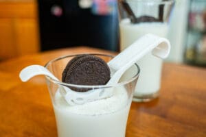 A cup of milk with an oreo cookie in it.