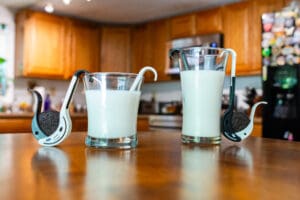 Two glasses of milk sitting on a table.