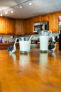 Two glasses of milk sitting on a table.