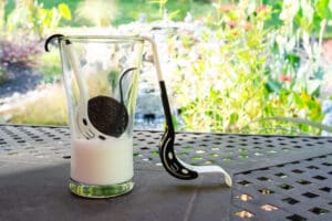 A glass of milk with an oreo cookie in it.