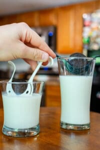 A person is putting cookies in milk