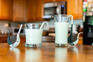 Two glasses of milk sitting on a table.