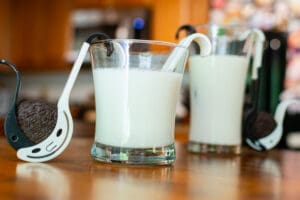 Two glasses of milk on a table with spoons.